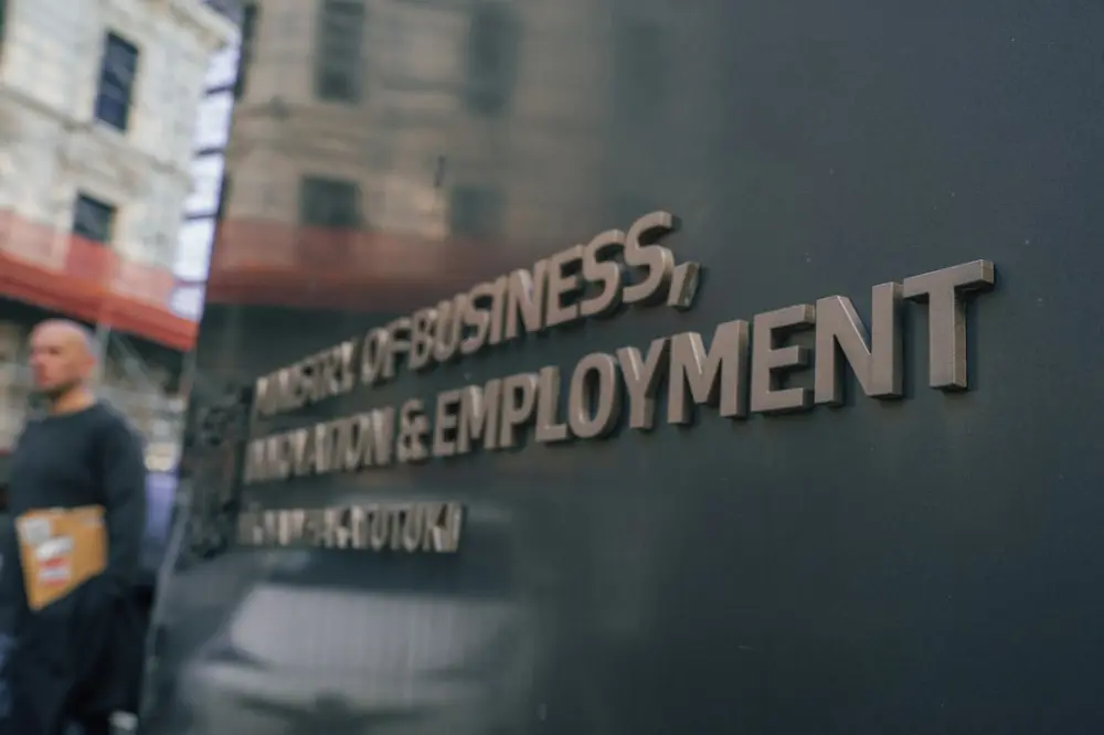 A person walking past a sign reading Ministry of Business, Innovation and Employment
